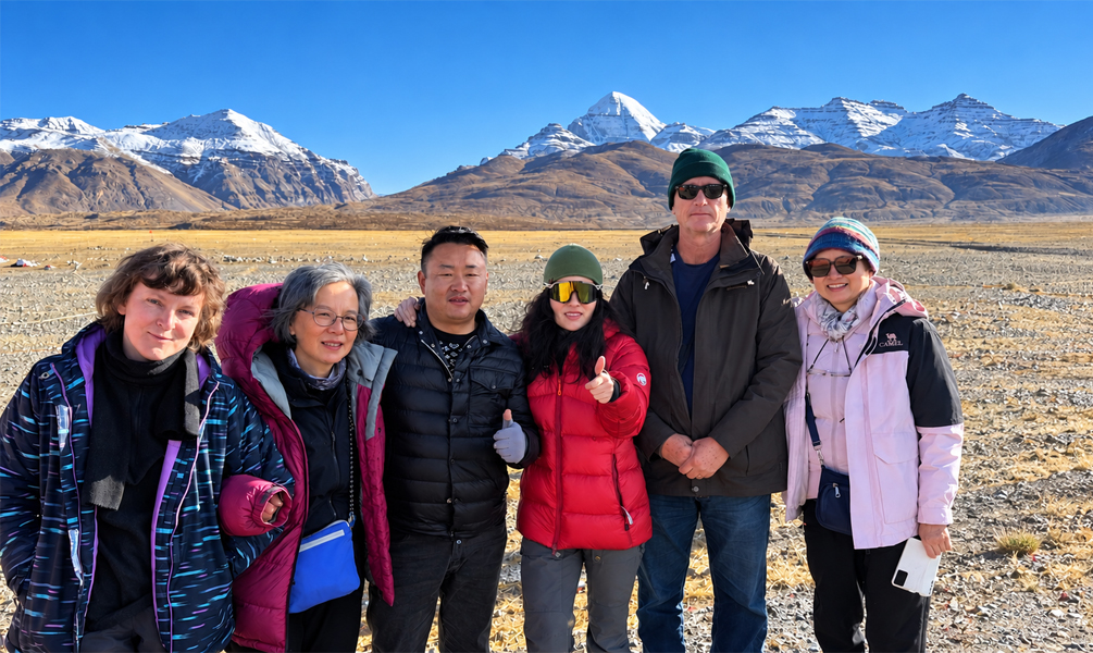 Travelers posing with snow-capped mountains on the Ngari Plateau in Tibet