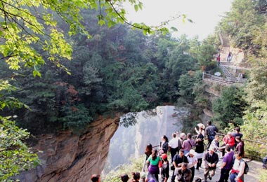 Travelers are visiting the famous bridge that spans between the two mountains in Yuanjiajie.