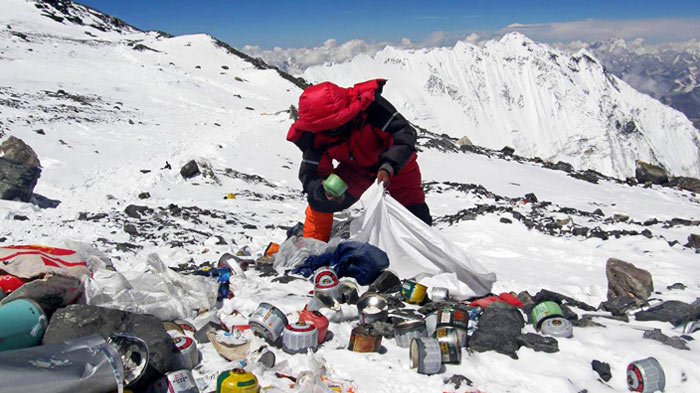 A Nepalese climber is collecting trash on Mt. Everest.