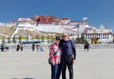 Traveler photo: Two guests lean close before the Potala Palace, their smiles warmer than the sunlight behind them. (April 2026)