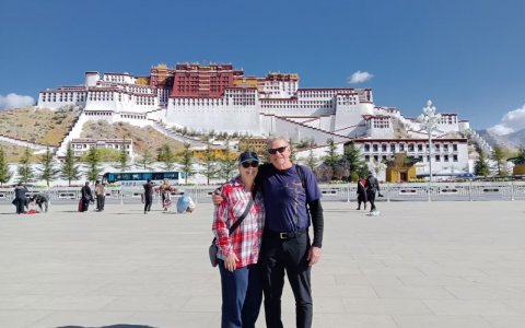 Traveler photo: Two guests lean close before the Potala Palace, their smiles warmer than the sunlight behind them. (April 2026)