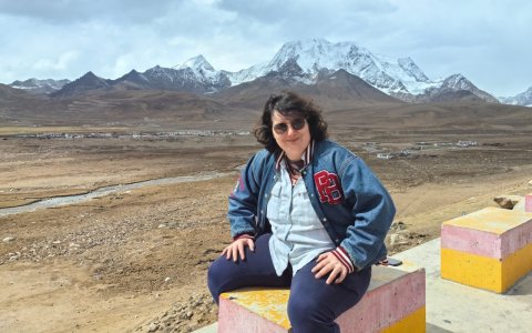 Traveler photo: A guest sits by the roadside, quietly taking in the distant snow-capped mountains, savoring a moment of plateau peace. (April 2026)