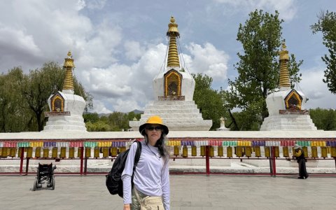 Traveler photo: A guest stands before a white stupa, capturing a simple travel memento with the sacred structure as backdrop. (April 2026)
