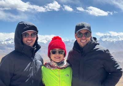 Traveler photo: Three guests stand side by side at Gawula Pass, with the majestic Himalayan range stretching endlessly behind them. (April 2026)