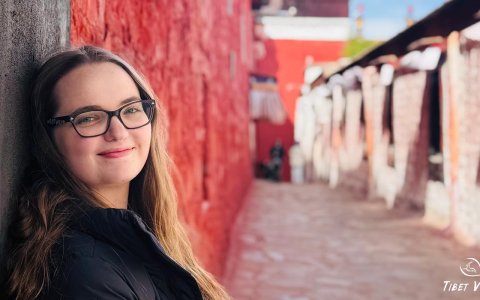 Traveler photo: Our lovely guest smiled as she leaned against the red wall of the Lhasa temple. (April 2025)