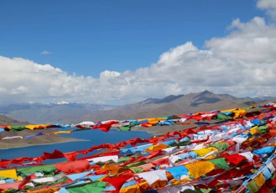 Traveler photo: Standing at viewpoint of Yamdrok Lake, prayer flags ripple in the wind—sacred lake behind, faith before your eyes. (April 2026)