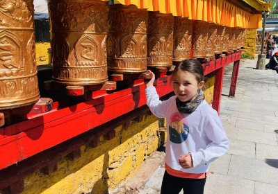 Traveler photo: Our lovely little guest spins the temple prayer wheels, which will bring her good luck. (April 2025)