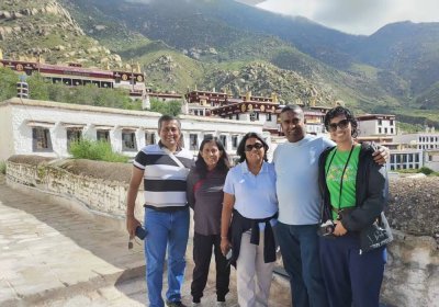 Traveler photo: Guests line up on the open ground before Drepung Monastery, taking a group photo with the white temple behind them. (August 2026)