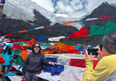 Traveler photo: Guests take turns excitedly photographing each other before Karo La Glacier, with ancient blue ice as a backdrop. (August 2026)