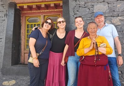 Traveler photo: In the temple hall, guests stand beside a monk holding prayer beads, his expression serene. (August 2026)