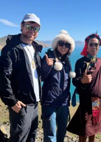 Traveler photo: Guests and their guide smile together by the turquoise Yamdrok Lake, with snow-capped peaks behind them in the photo. (August 2026)