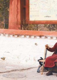 Traveler photo: Monks in red robes sitting on the bench outside the monastery, one of the typical scenery in Tibet. (August 2026)	