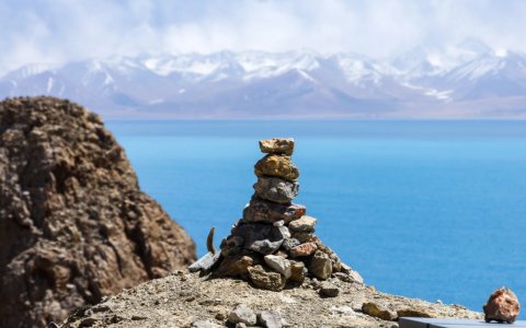 Traveler photo: Mani stone piles lie along the shore of Yamdrok, left to seek blessings and fortune. (August 2025)