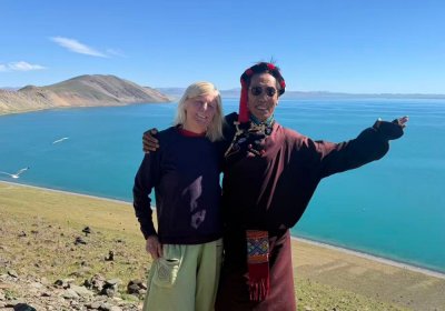 Traveler photo: Our traveler and guide share a happy moment beside the turquoise Yamdrok Lake. (August 2026)