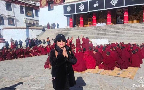 Traveler photo: Outside the Tsogchen Hall of Drepung Monastery in Lhasa, guests joyfully frame themselves with red-robed monks on break. (December 2025)