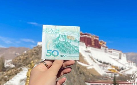 Traveler photo: Before Potala Palace in Lhasa, a traveler holds up a fifty-yuan bill to match the actual scene with its printed image. (December 2025)