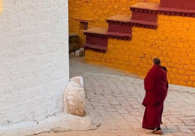 Traveler photo: Tibetan monk in red robe is heading to debate courtyard and prepare for the monk debate. (December 2025)	