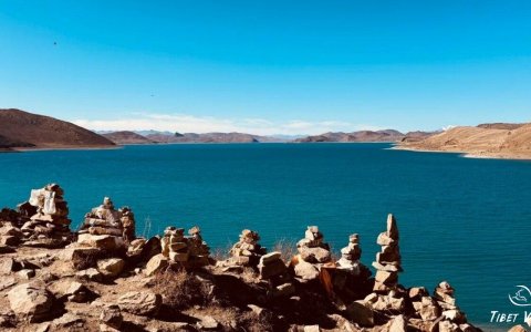 Traveler photo: Mani stone piles along Yamdrok Lake shores in Tibet, layered rocks guarding holy lake in plateau winds, becoming eternal coordinates of faith. (January 2026)