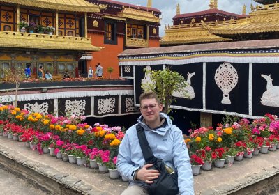 Traveler photo: A guest sits on the ground in front of Jokhang's golden roof, with the gilded Tibetan architecture forming the backdrop. (July 2026)