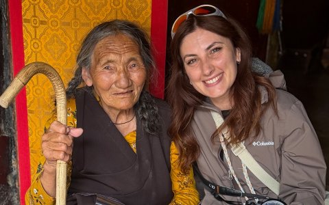 Traveler photo: A guest smiles beside a Tibetan grandmother, sharing a simple and heartwarming photo moment. (July 2026)