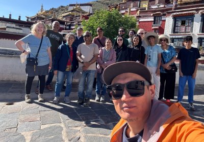 Traveler photo: The guide and guests hold up a phone for a selfie at the temple gate, their smiles brighter than the sunlight. (July 2026)
