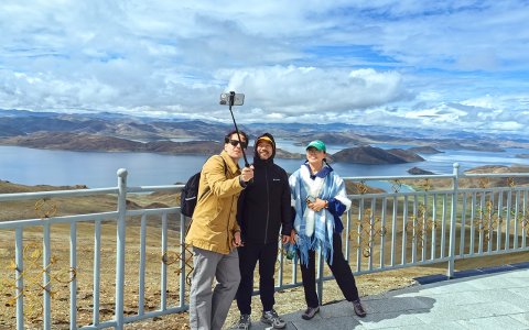 Traveler photo: Our guests explore the Kampala pass, framed by the blue water of Yamdrok lake. (July 2026)	