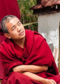 Traveler photo: In Sera Monastery's debating courtyard, a red-robed monk pauses in thought, reflecting on the argument just heard. (July 2026)