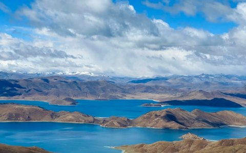 Traveler photo: Tibet's Yamdrok Lake shimmers in layered blues, a turquoise ribbon winding through majestic mountains. (June 2026)