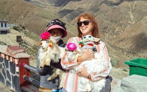 Traveler photo: A guest cradles an adorable lamb while posing for a heartwarming photo with a local. (June 2026)