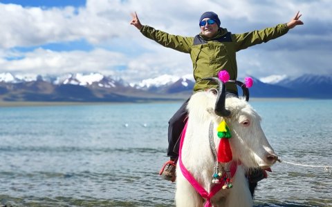 Traveler photo: With the sacred lake in turquoise blue and a friendly yak beneath, the guest enjoys a fun and memorable ride. (June 2026)