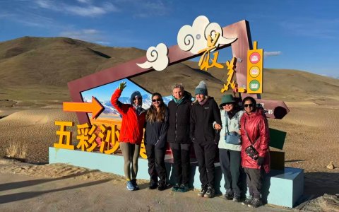 Traveler photo: Our guests stand together in a Tibetan desert, capturing a joyful group photo between blue sky and golden sand. (June 2026)