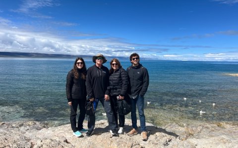 Traveler photo: Guests smile together by turquoise Namtso Lake, with snow-capped peaks rising in the distance. (June 2026)