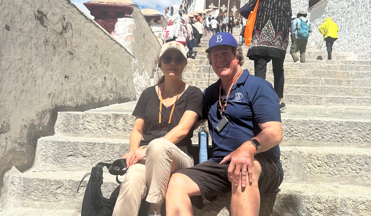 Two elderly people are sitting on the steps of the Potala Palace, resting.