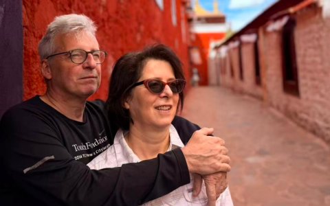 Traveler photo: Two guests smile side by side between red walls and white stupas in a Lhasa temple, leaving a loving photo behind. (June 2026)