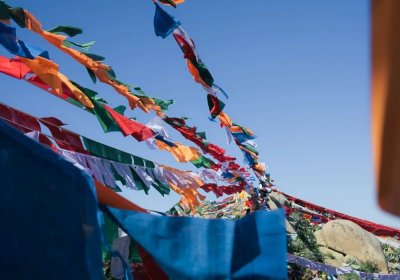 Traveler photo: Five-colored prayer flags dance freely in the wind—blue, white, red, green, yellow—beneath the plateau's vast sky. (June 2026)