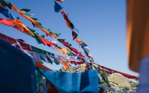 Traveler photo: Five-colored prayer flags dance freely in the wind—blue, white, red, green, yellow—beneath the plateau's vast sky. (June 2026)