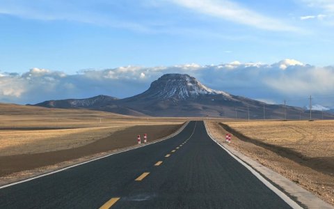 Traveler photo: A smooth highway stretches straight toward distant snow mountains, flanked by vast plateau scenery. (June 2026)