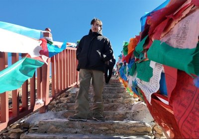 Traveler photo: A guest ascends the steps, instantly engulfed by a gentle ocean of colorful prayer flags. (March 2026)