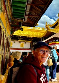 Traveler photo: The golden roof of Jokhang Temple gleams under the sun as the guest smiles for a photo beside it. (May 2026)