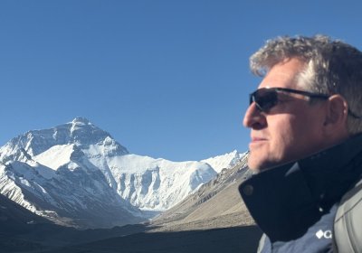 Traveler photo: A guest's profile faces Everest, his silhouette framed with the snowy peak—quiet and powerful. (May 2026)