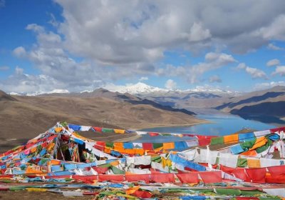 Traveler photo: By the turquoise Yamdrok Lake, colorful prayer flags flutter in the wind—a lovely contrast of blue and vibrant hues. (May 2026)