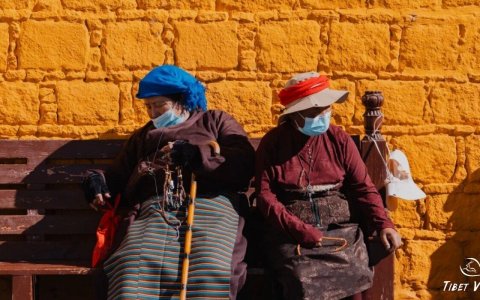 Traveler photo: Local Tibetans sitting on the bench, against the yellow wall. (October 2025)	