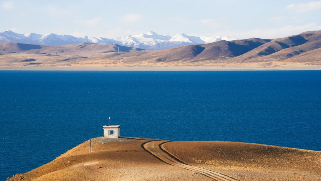 Deep blue Lake Manasarovar under white snow mountains