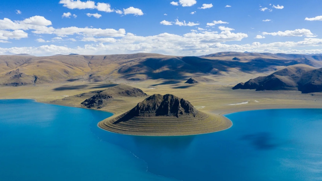 Bird-eye view of turquoise lake with small hill