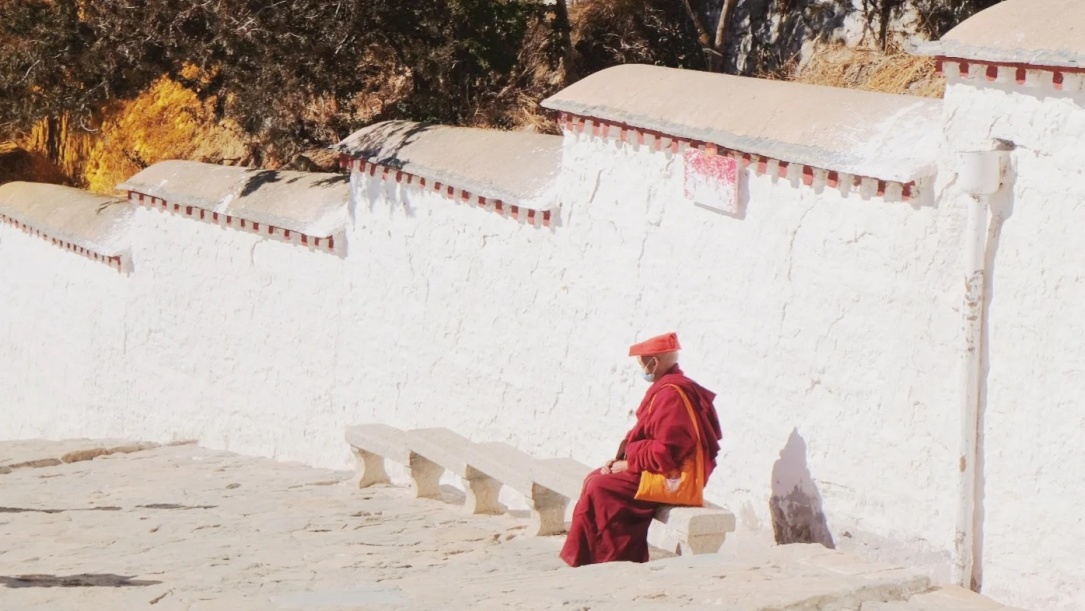 Monk sitting by white wall