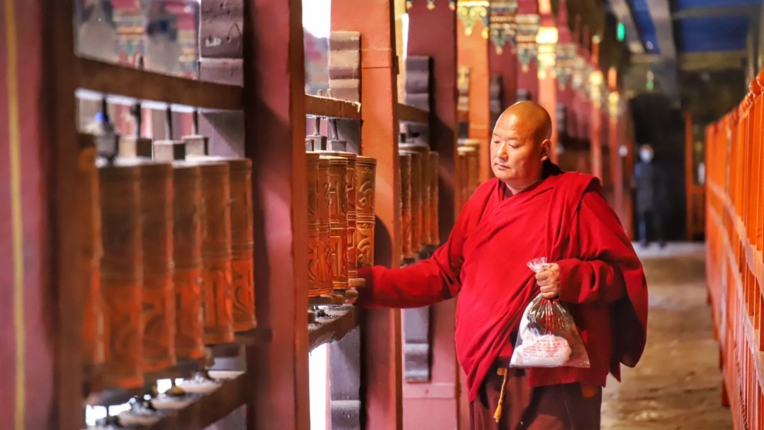 Tibetan monk turning prayer wheels