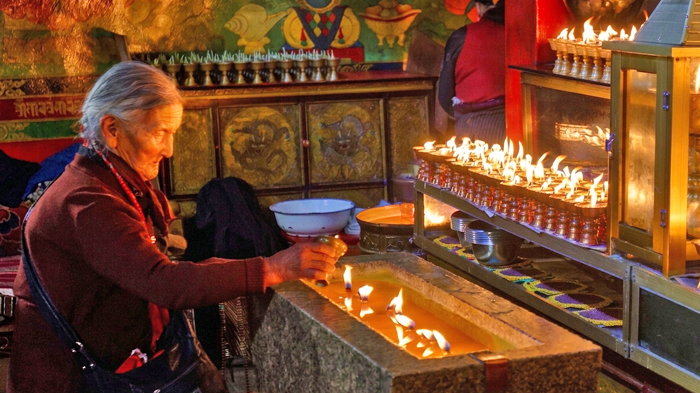 Tibetan pilgrims offering butter lamp oil at a Tibetan Monastery