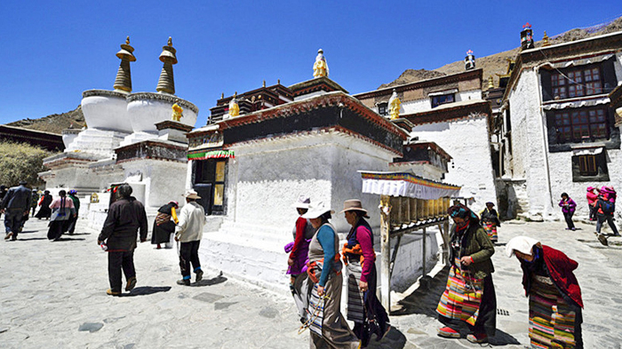 Local Tibetan pilgrims walk clockwise around the white stupas at Tashilhunpo Monastery