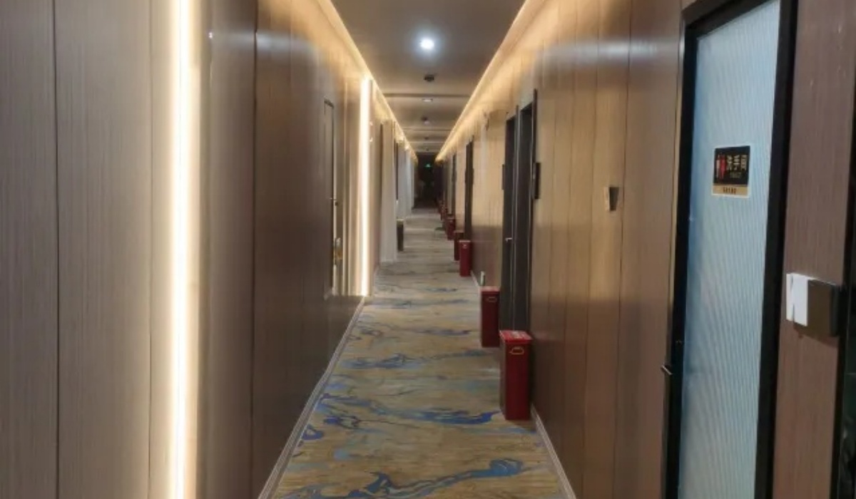 Well-lit carpeted guest room corridor at Letu Hotel