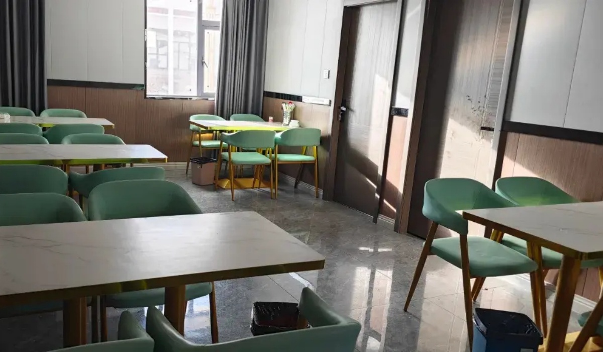 Bright dining area with green chairs and wooden tables at Letu Hotel